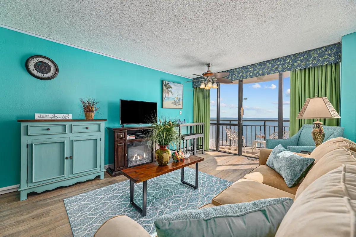 Turquoise living room with beige sofa, armchair, and glass balcony doors