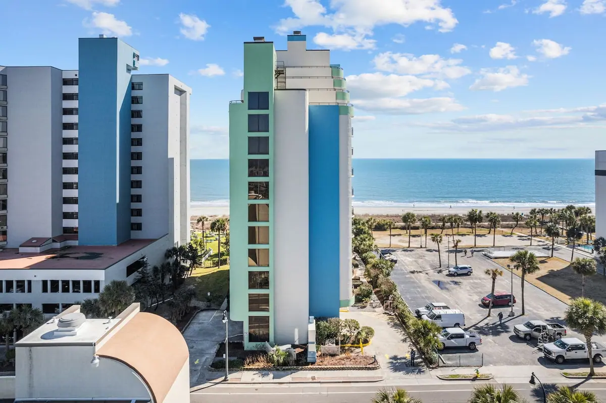 View between tall beachfront buildings toward the sand and ocean
