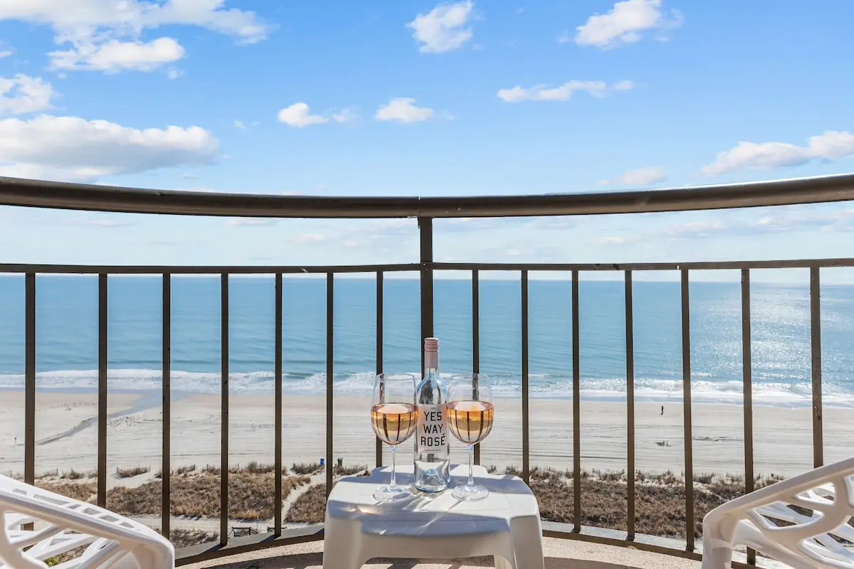 Oceanfront balcony with two chairs and a small table set for drinks