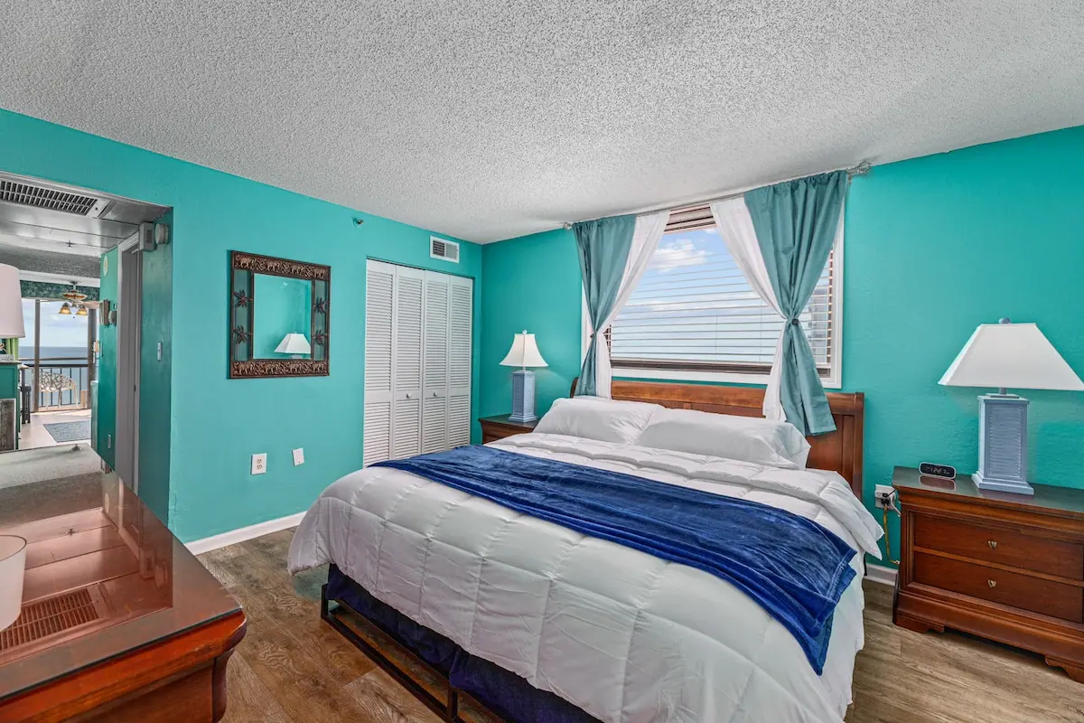 Bedroom with a white bed, blue throw, and turquoise walls