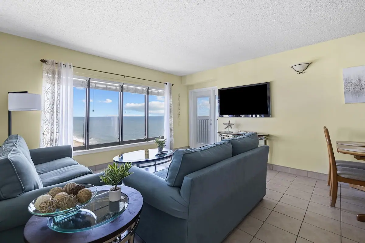 Living room with a blue sofa and ocean-facing glass balcony doors
