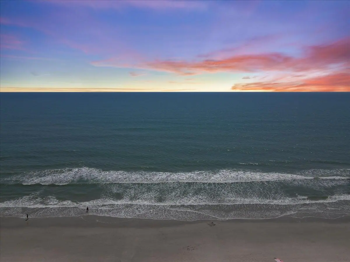 Ocean waves beneath a pink and orange sunset sky