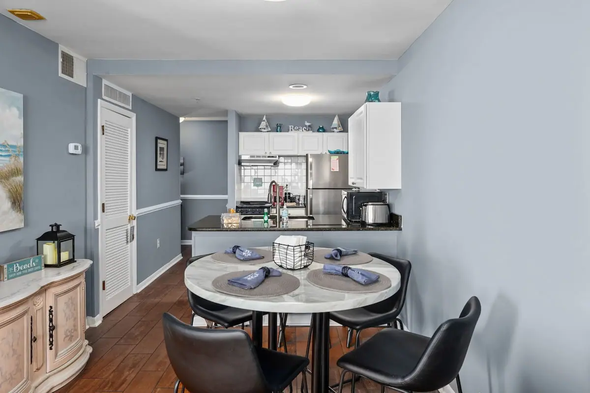 Round dining table beside a compact white kitchen and living area