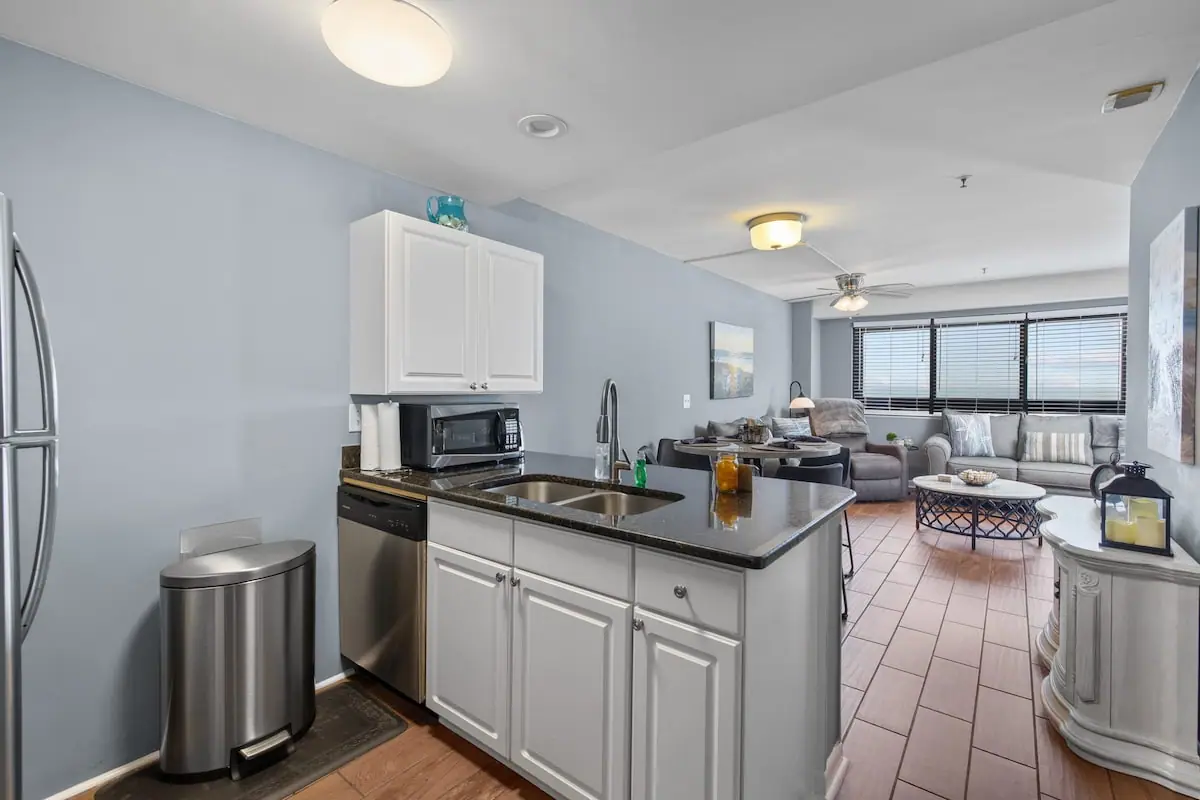 White kitchen and breakfast bar opening to a gray living room