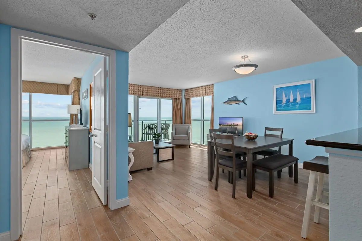 Open dining area with tile floor and ocean-facing living room beyond
