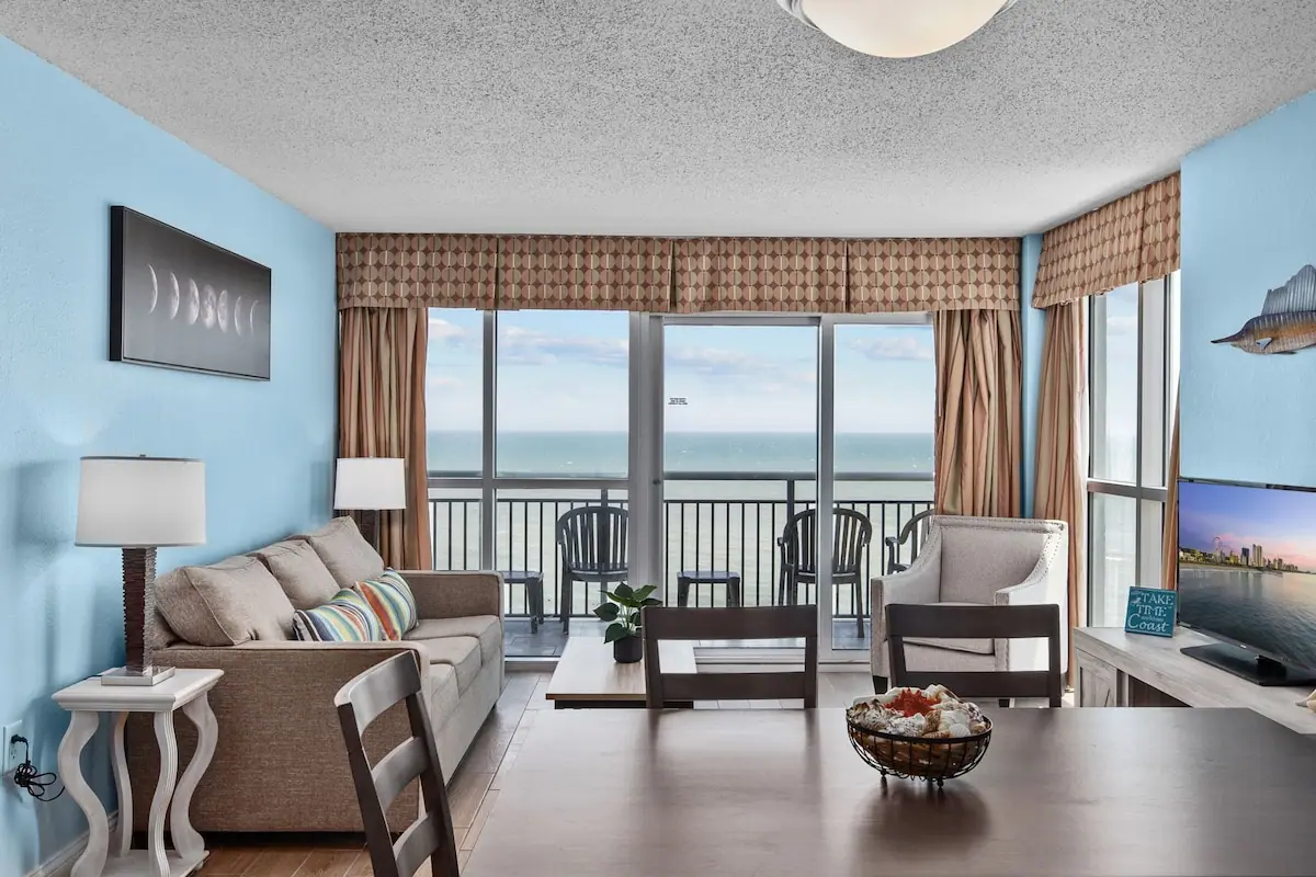 Living room seating facing wide windows and an ocean balcony