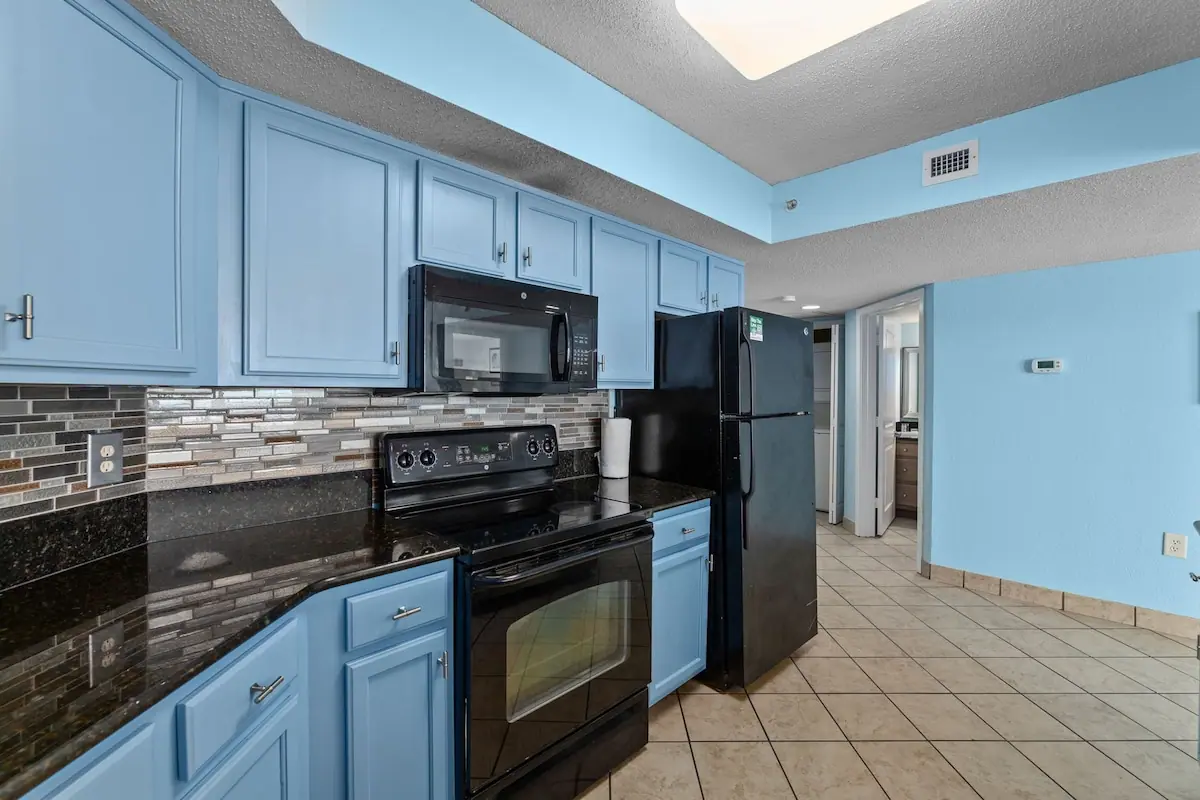 Kitchen with blue cabinets, black appliances, and tile floor