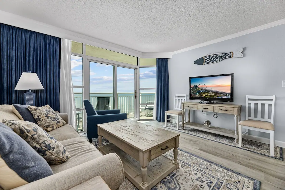 Living room with a gray sofa and balcony doors facing the ocean