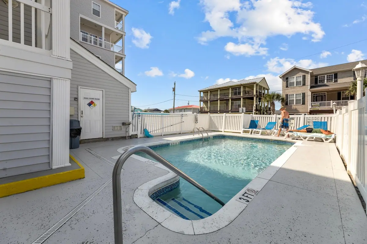 Small outdoor pool and lounge chairs beside a multistory building