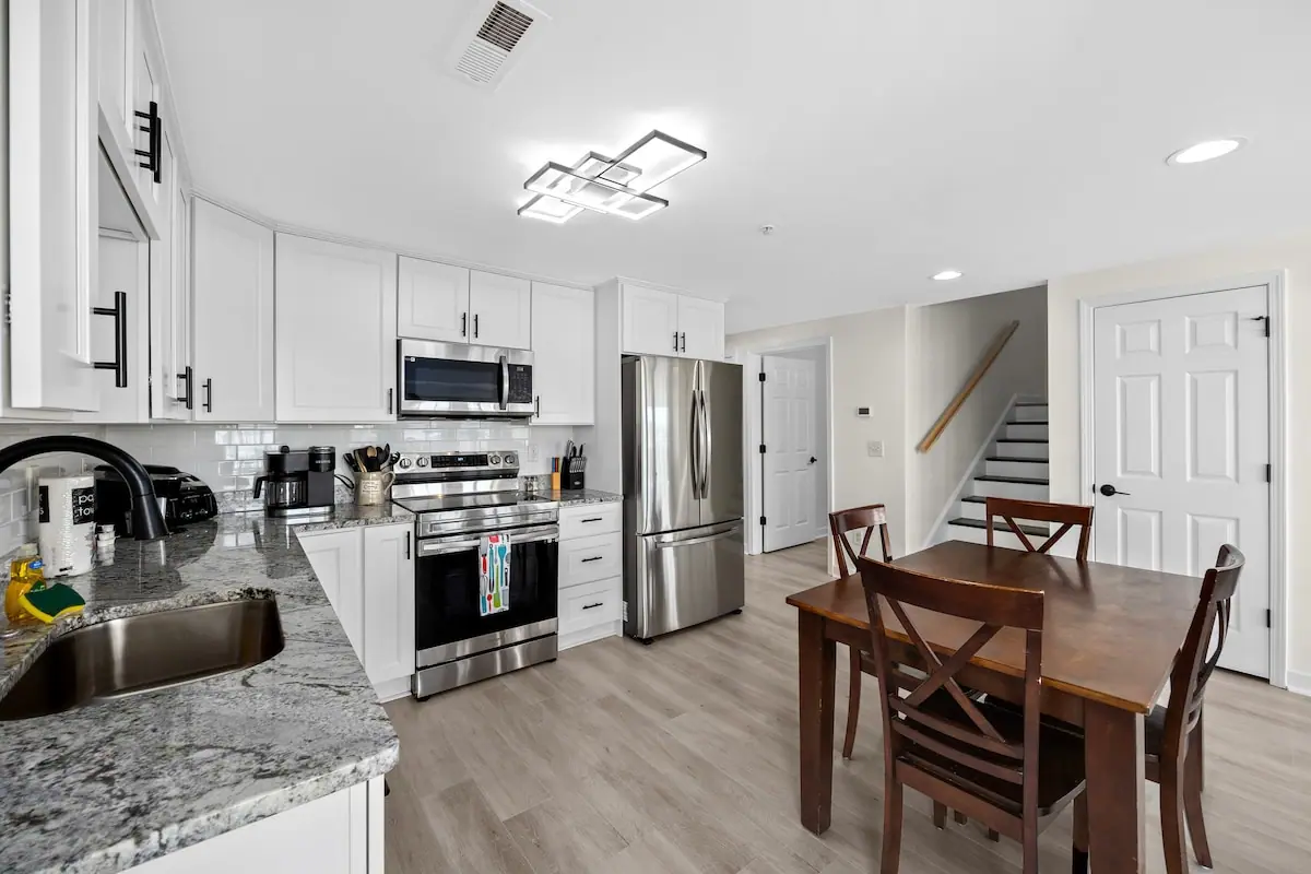 White kitchen with stainless appliances beside a wooden dining table