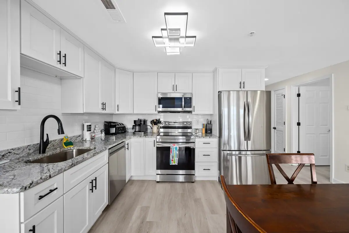 White kitchen with granite-look counters and a stainless refrigerator