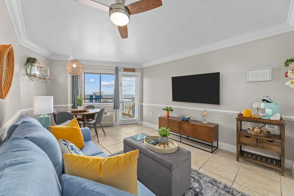 Living room with a blue sofa, television, and glass balcony doors