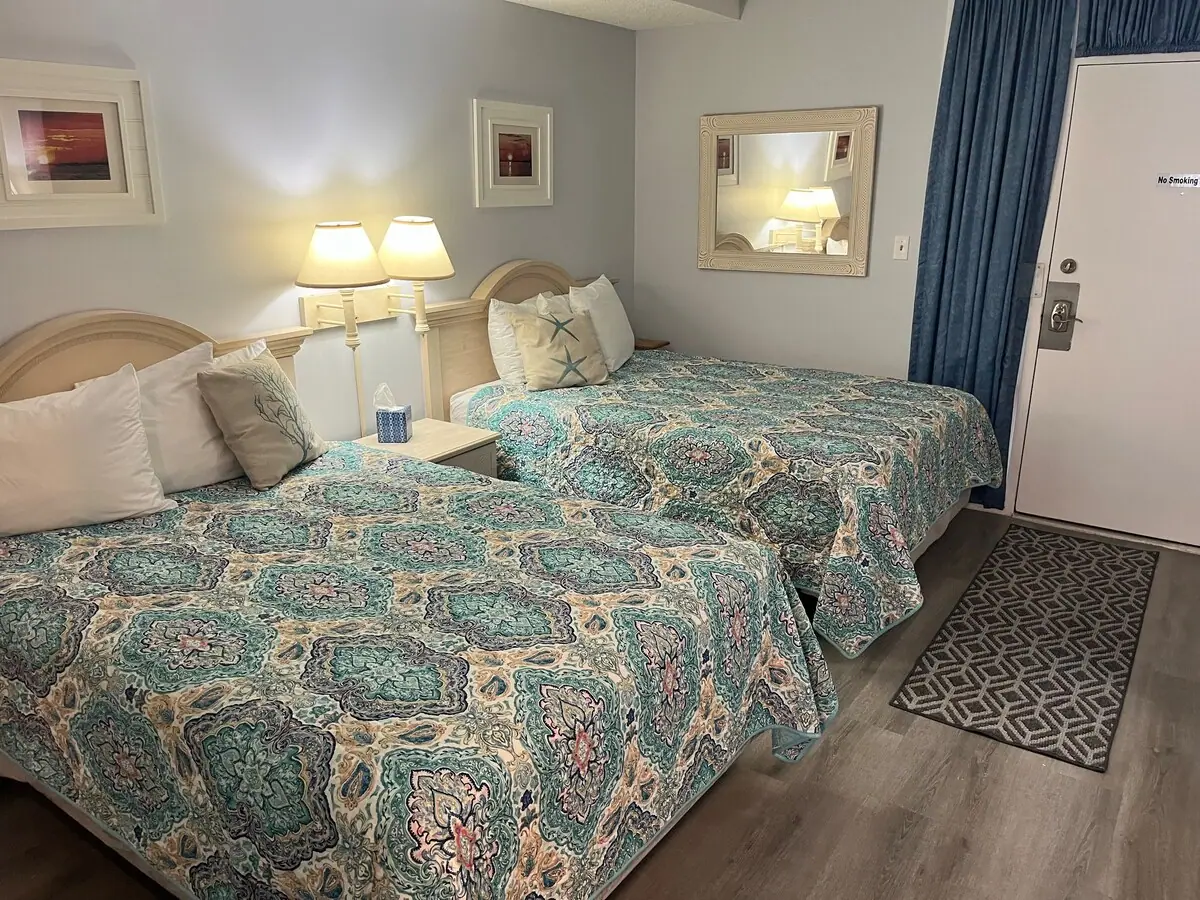 Two beds with teal patterned bedding and bedside lamps