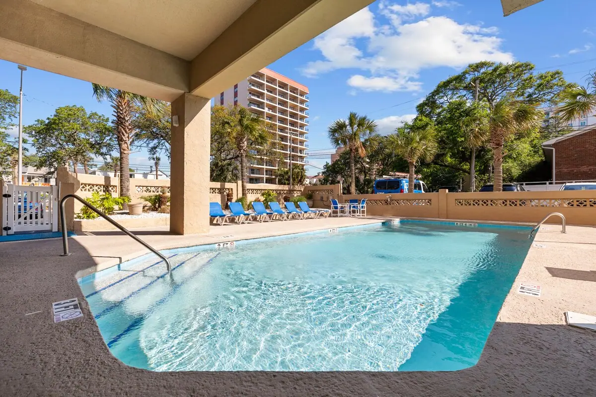 Outdoor pool bordered by lounge chairs and palm trees