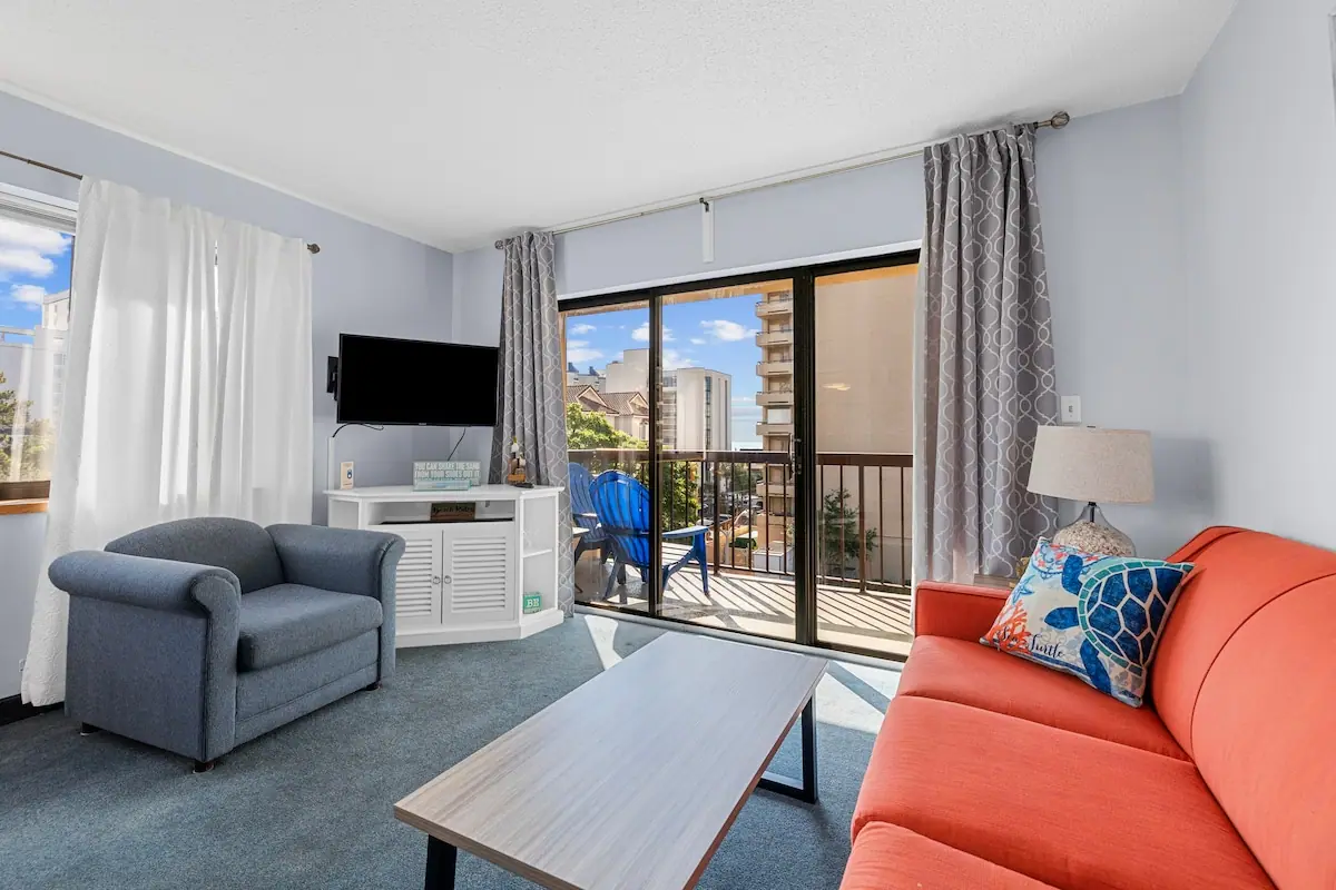 Orange sofa and blue recliner beside glass balcony doors
