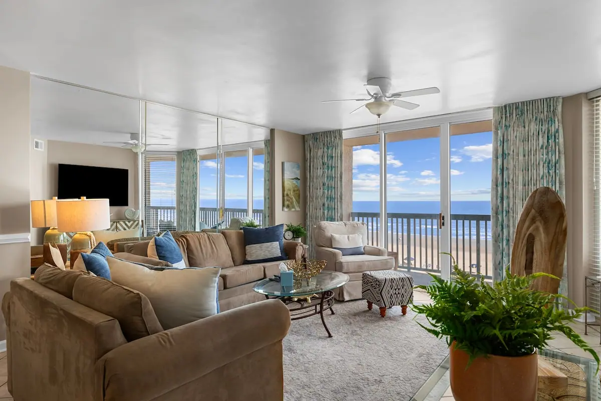 Living room with sofas and floor-to-ceiling windows facing the ocean
