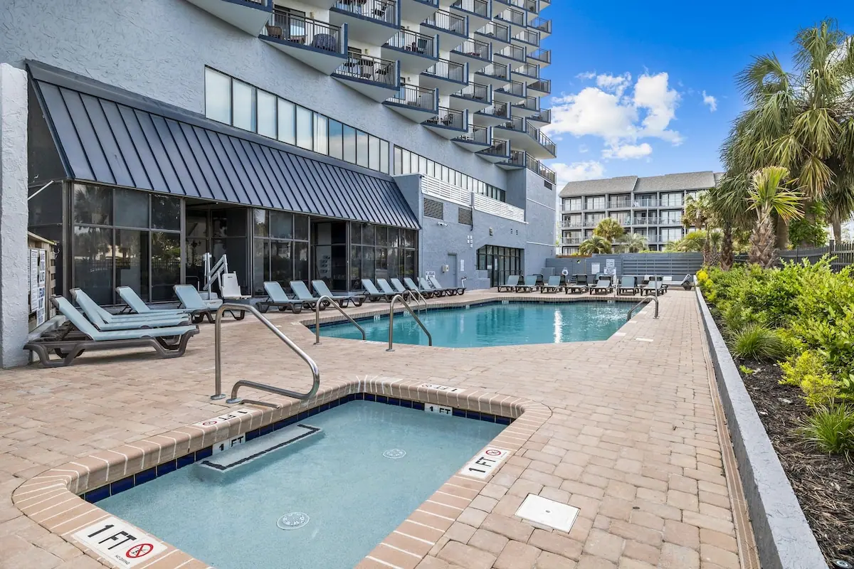 Outdoor pool and a smaller adjoining pool beside lounge chairs and palm trees