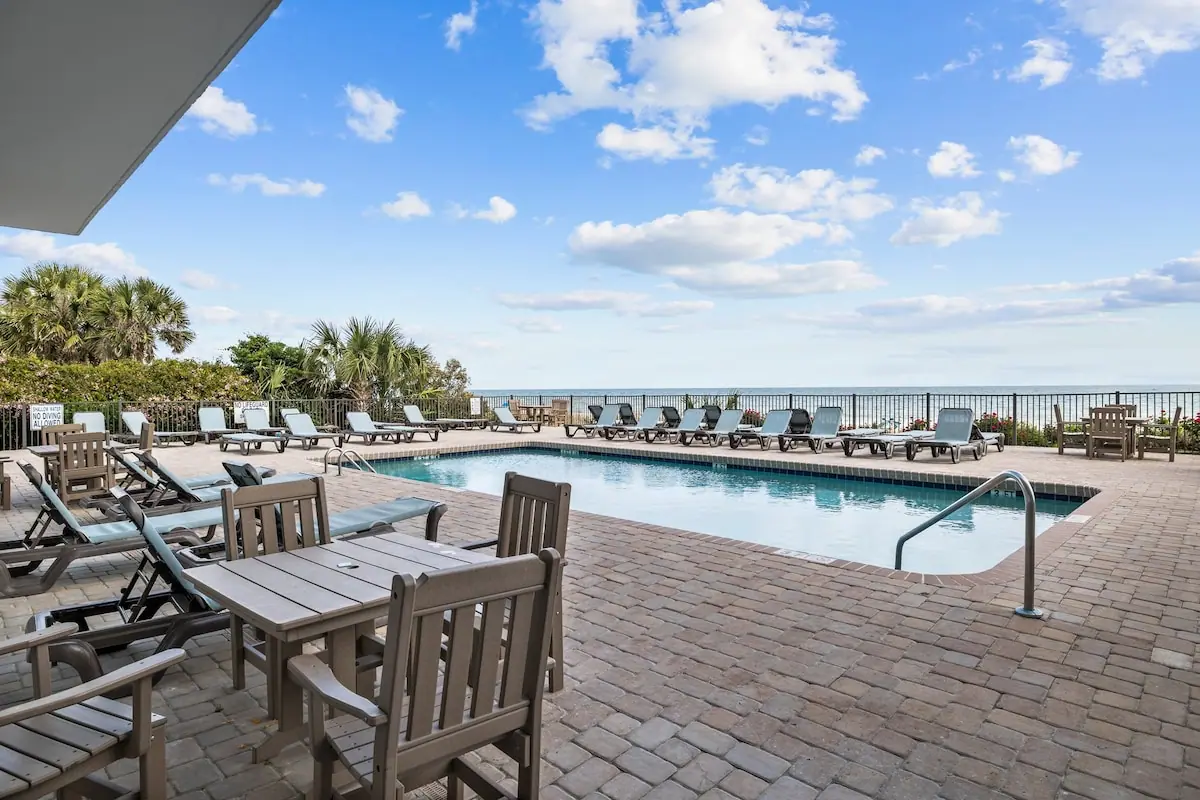 Pool terrace with lounge chairs, palms, and the ocean beyond