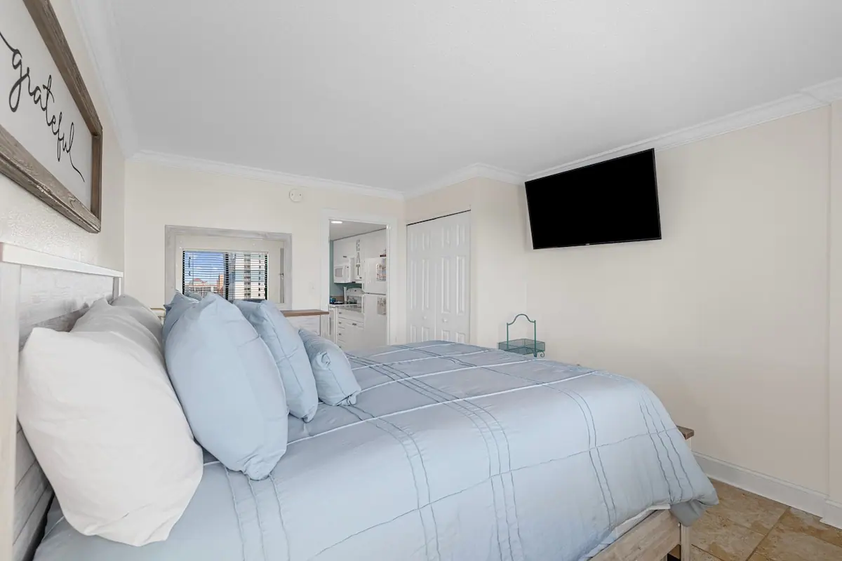 Bedroom with pale blue bedding and a doorway toward the living area