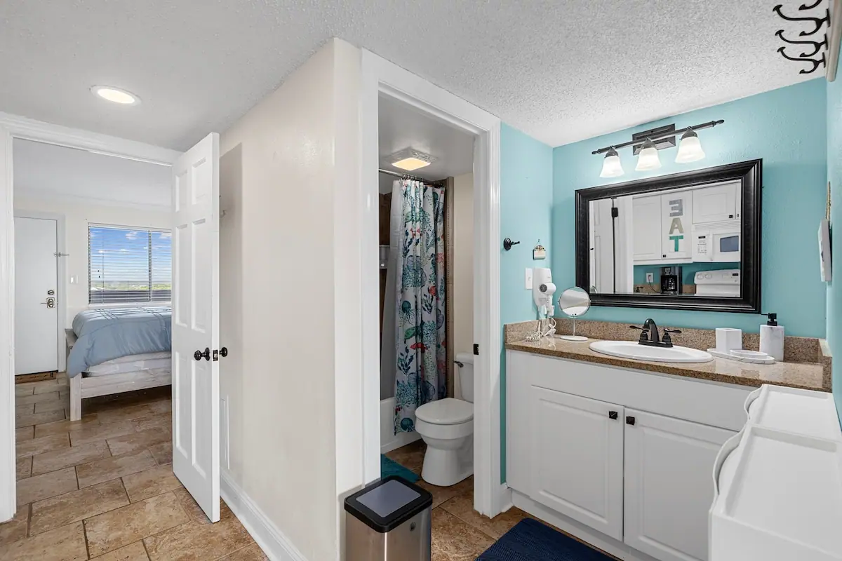 Bathroom with turquoise wall, white vanity, large mirror, and curtained shower