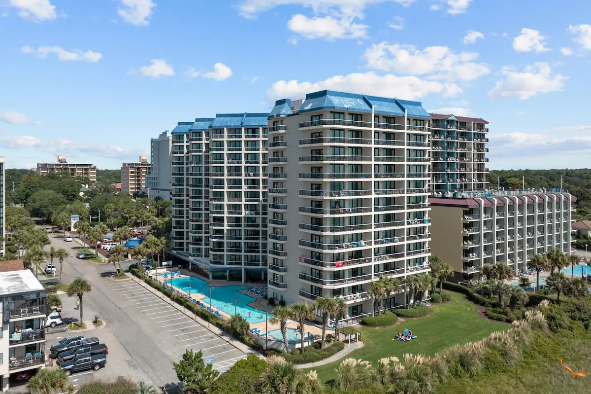 Aerial view of a multistory building with an outdoor pool and lawn