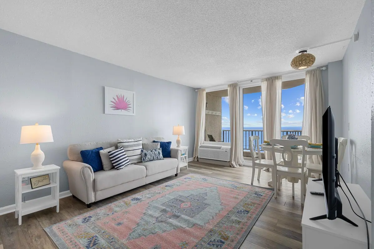Living room with a pale sofa, small dining table, and ocean balcony