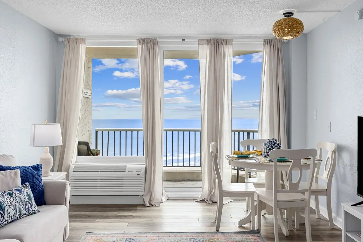 Dining table beside tall windows and a balcony overlooking the ocean