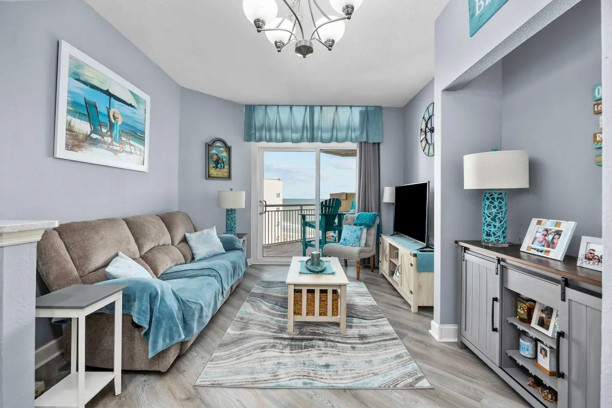 Living room with sofa, blue throw, TV, and glass balcony door