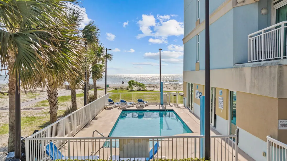 Small outdoor pool framed by palm trees with the beach beyond