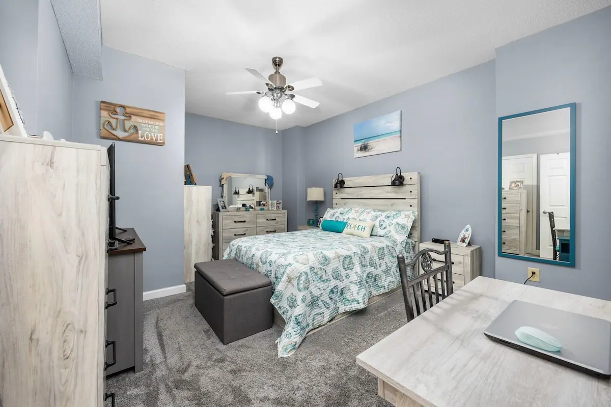 Bedroom with blue and white patterned bedding and a dresser