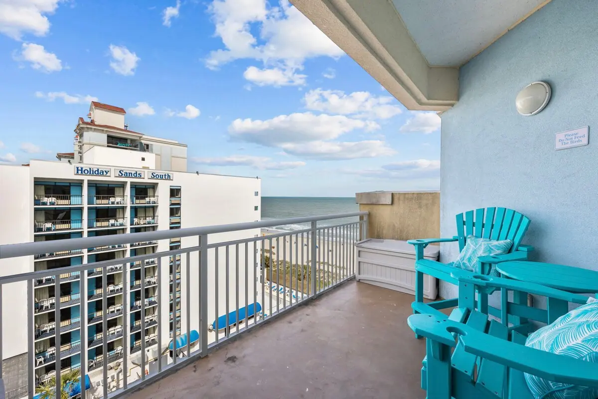 Balcony with turquoise chairs overlooking nearby buildings and the ocean