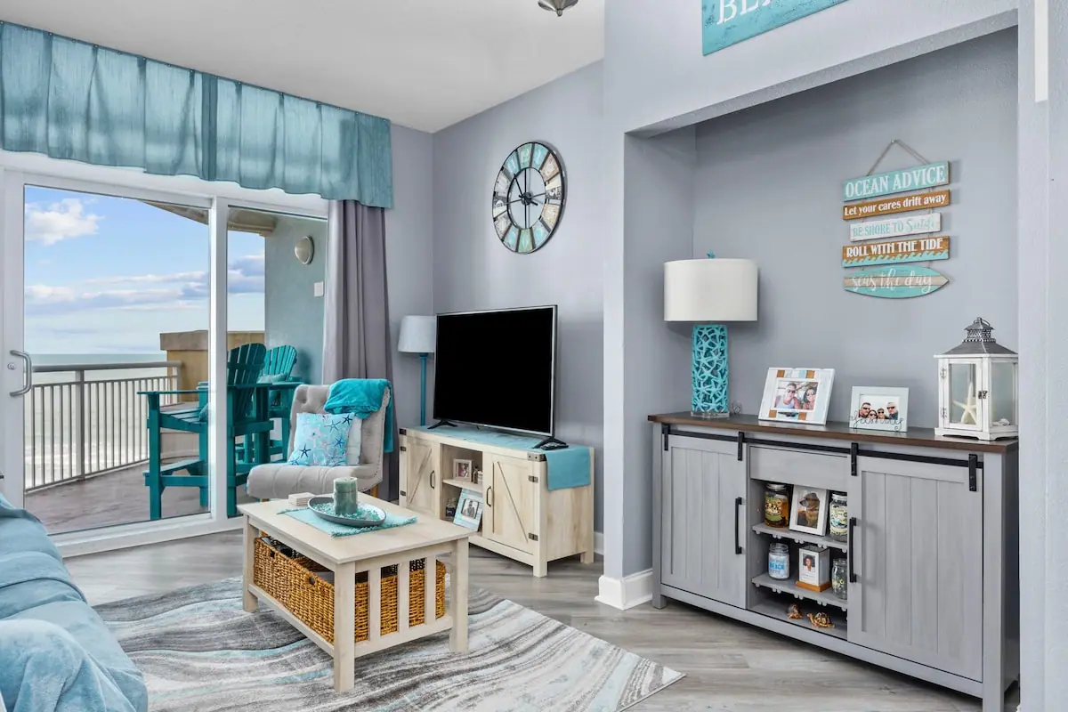 Living room TV console and turquoise chair beside the balcony door