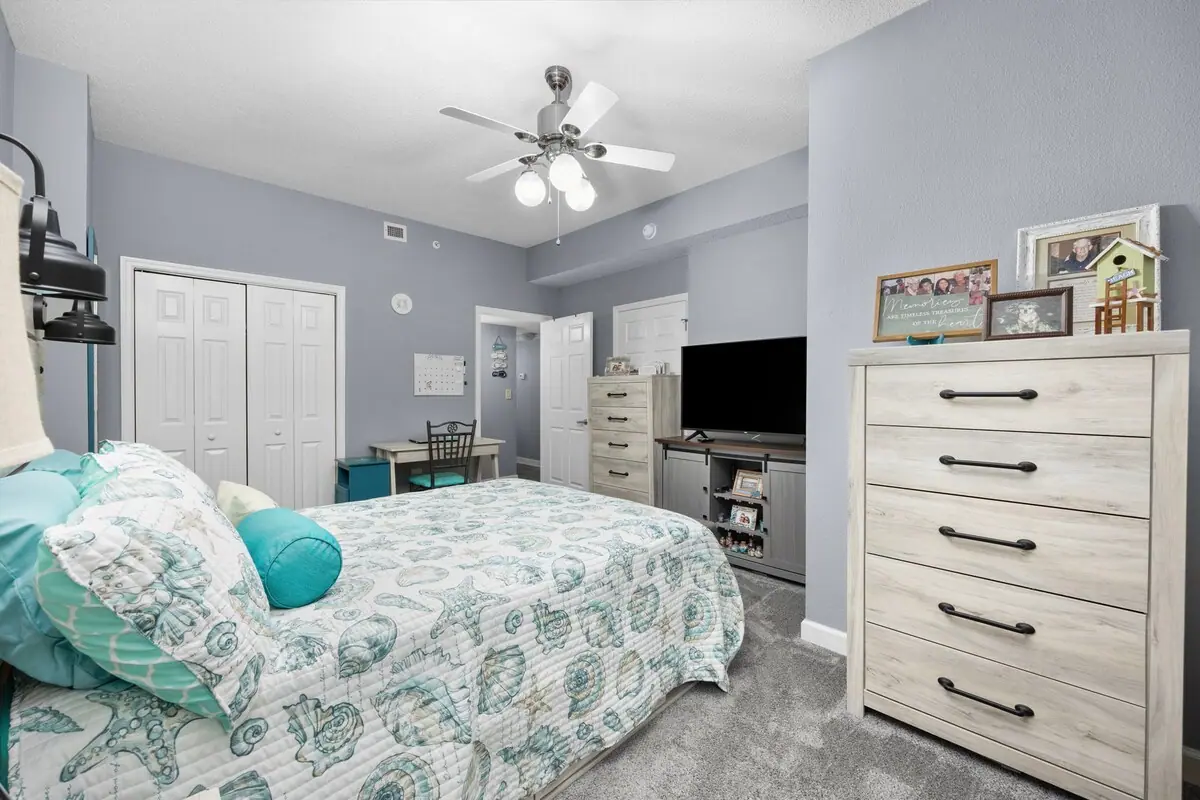 Bedroom with patterned bedspread, dresser, and television