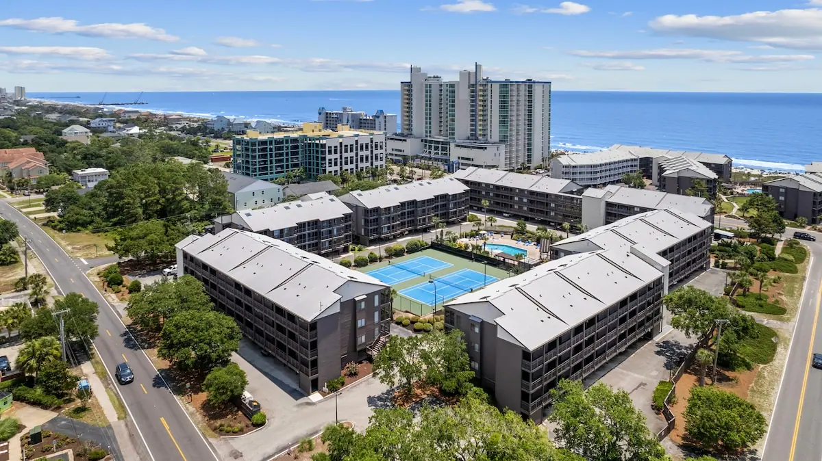 Aerial view of low-rise buildings around an outdoor pool near the ocean