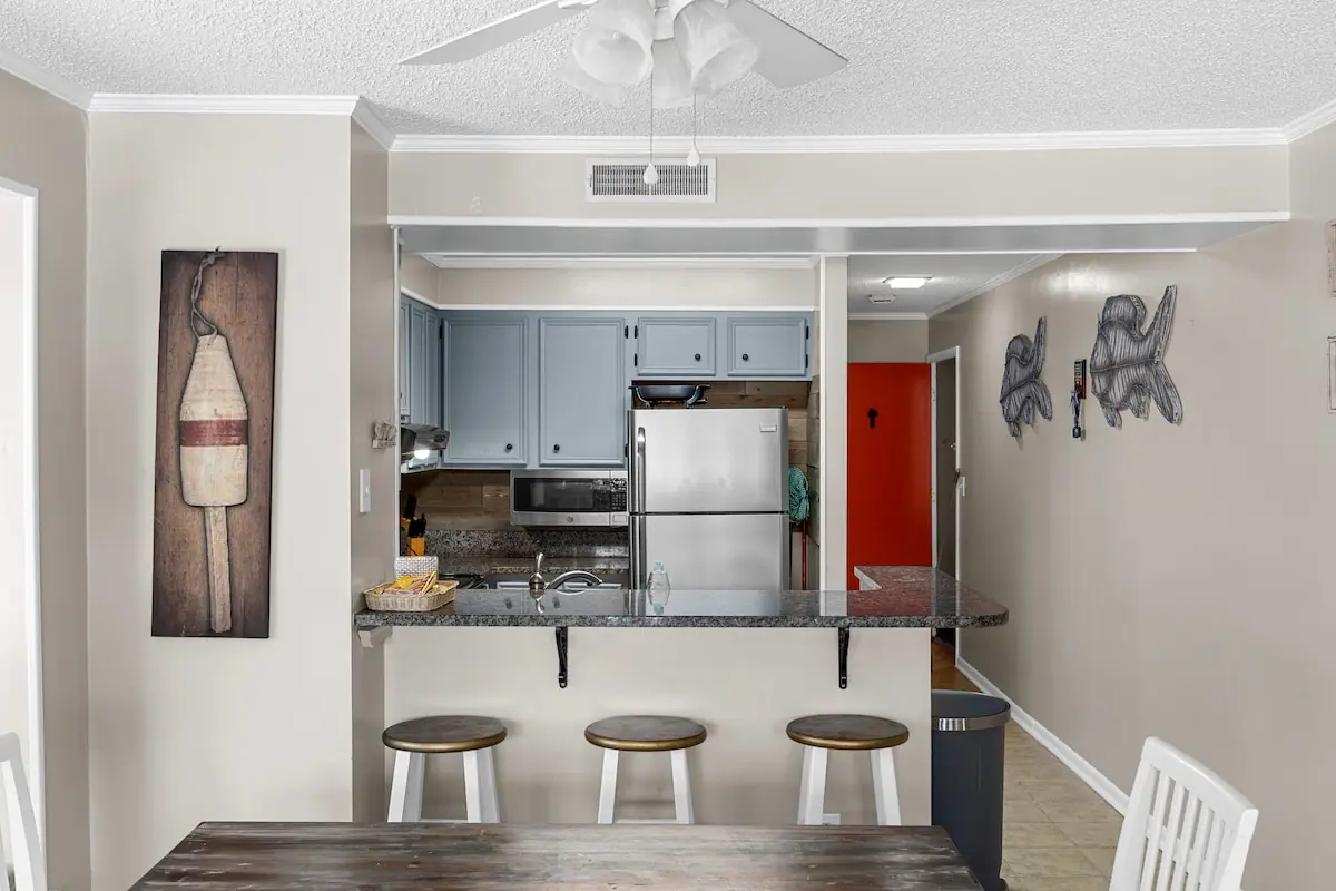 Breakfast bar with three stools opening to a kitchen and dining area