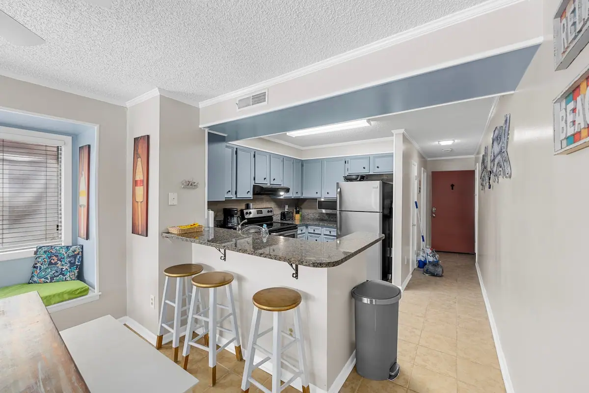 Kitchen breakfast bar beside a window seat and tiled entry hall