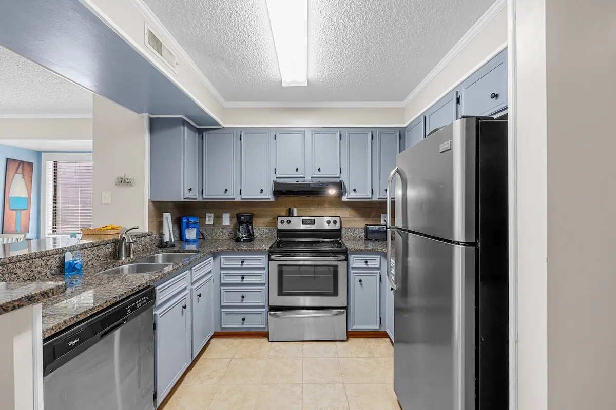 Kitchen with pale blue cabinets, white stove, and stainless refrigerator