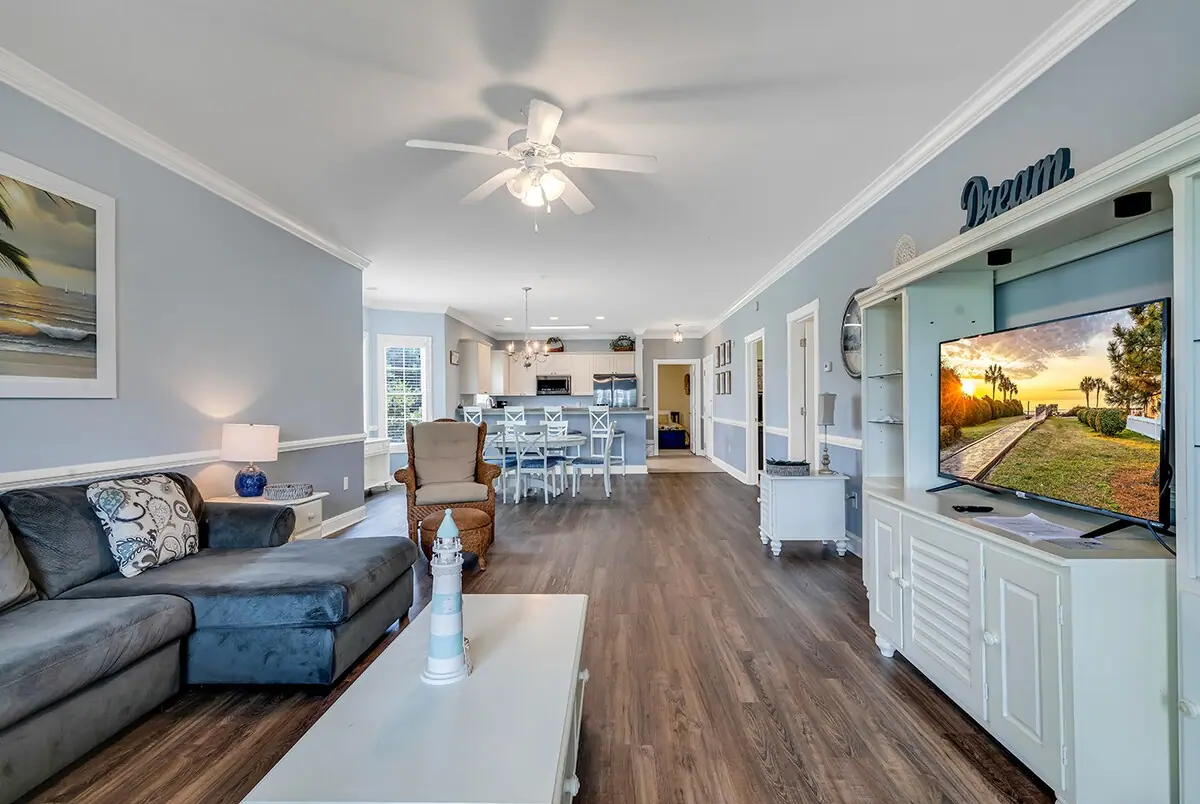 Open living and dining room with a gray sectional, television, and kitchen beyond