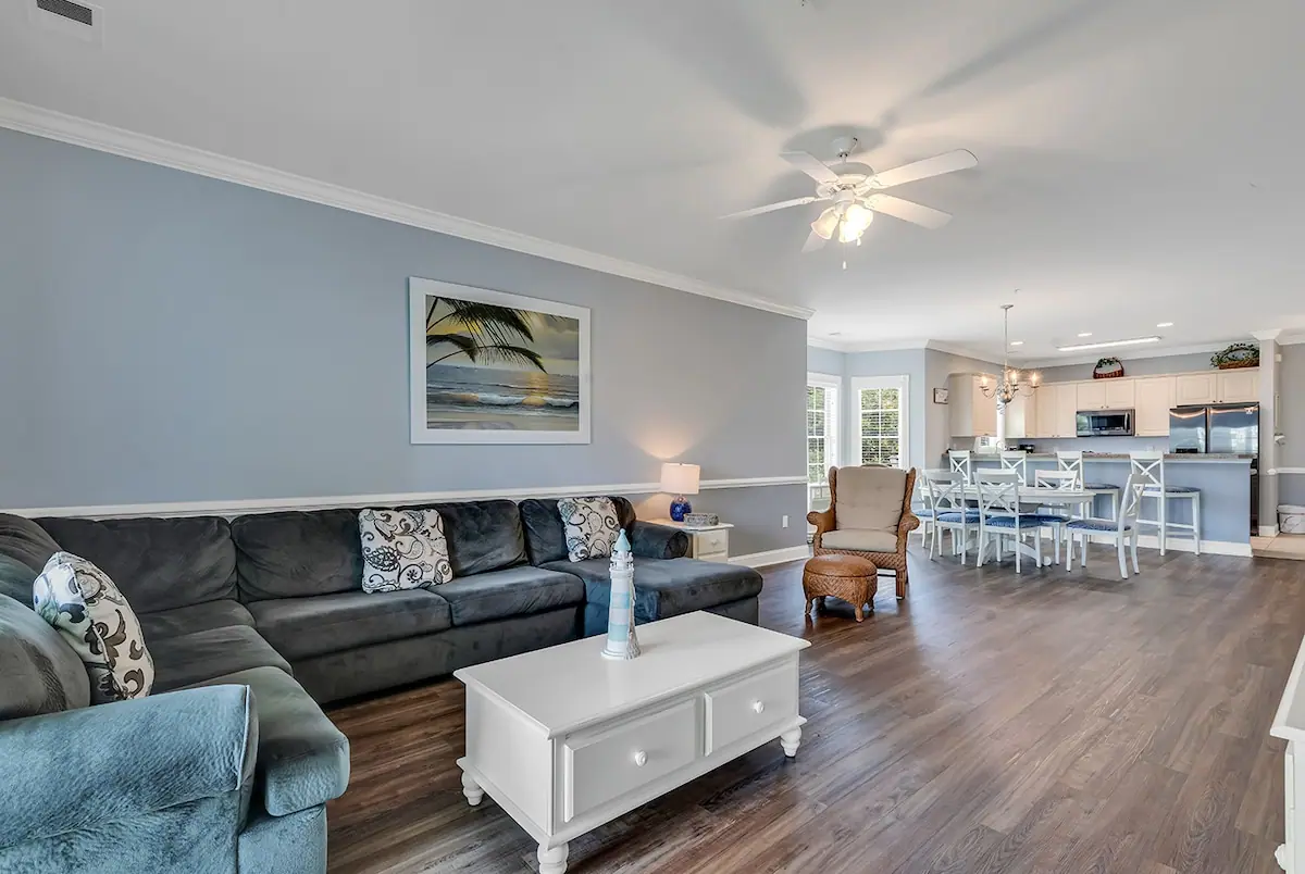 Living area with a gray sectional, dining table, and kitchen beyond