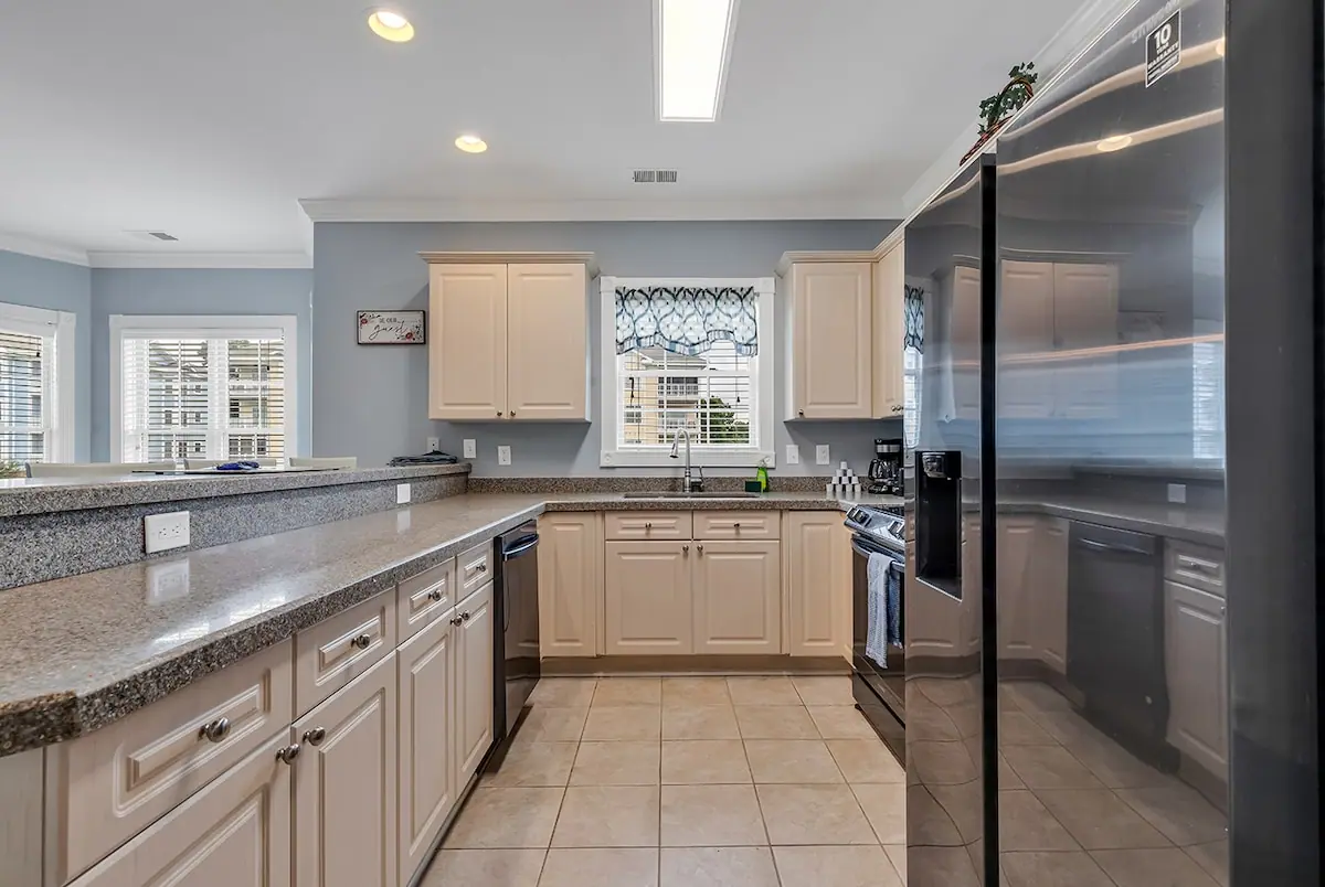 White kitchen with granite-look counters and a stainless refrigerator