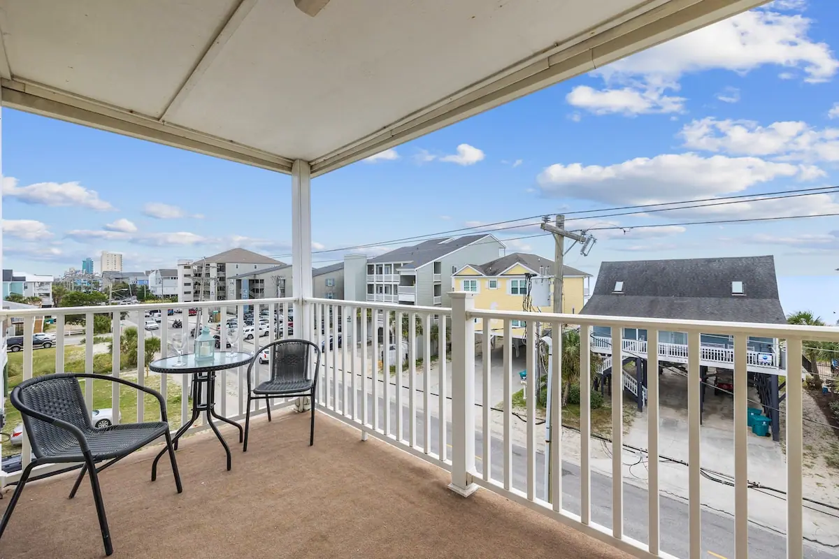 Covered balcony with small table and chairs facing neighboring buildings
