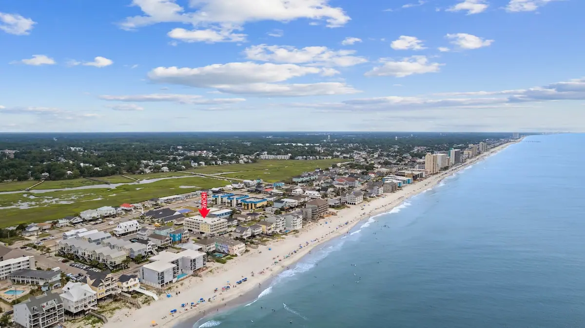 Aerial view of sandy coastline, ocean, and rows of low buildings