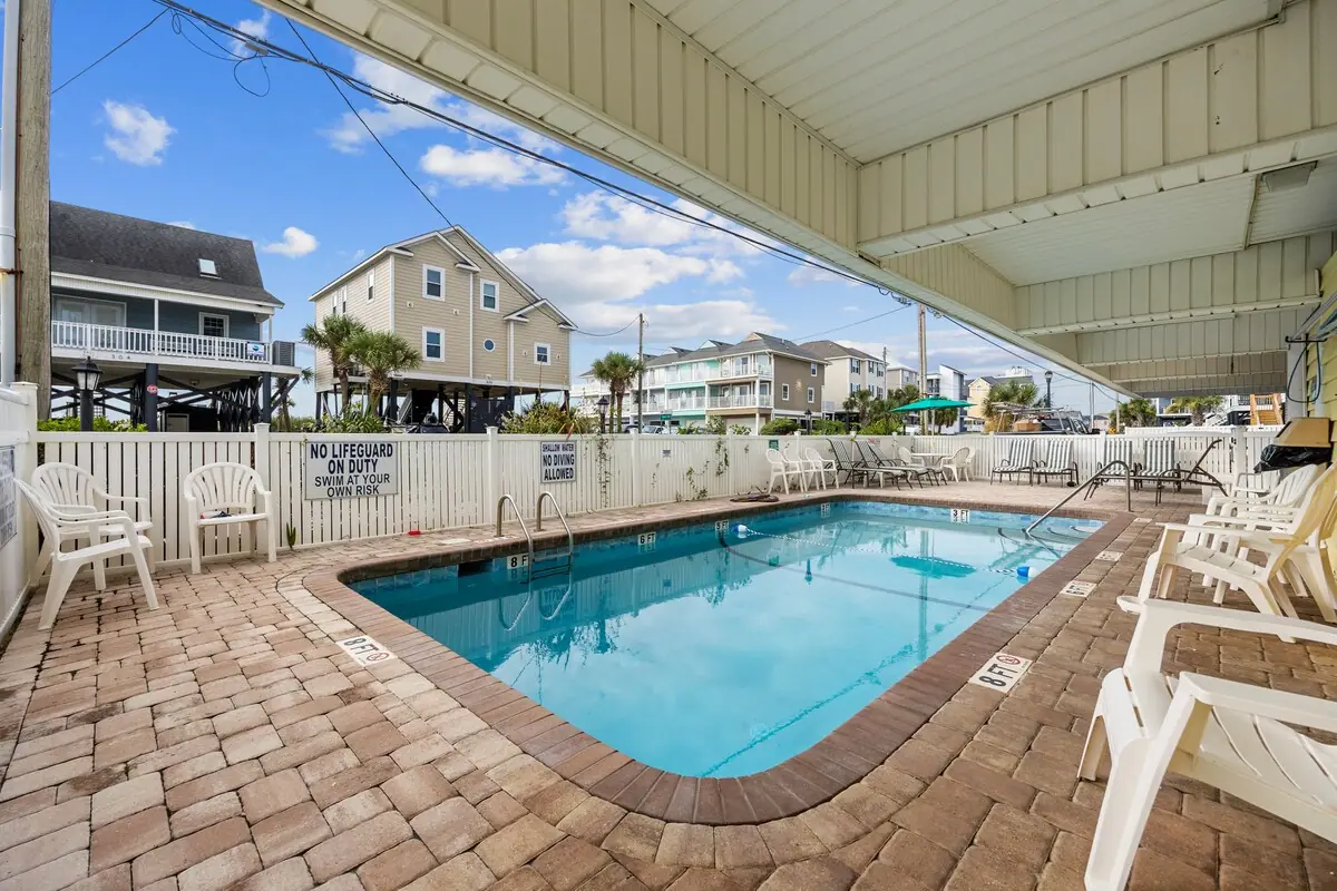 Outdoor pool among low-rise homes with lounge chairs along its edge