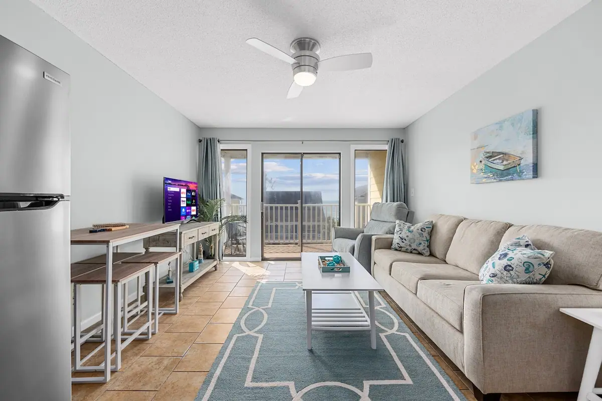Living room with gray sofa, television, and glass balcony doors