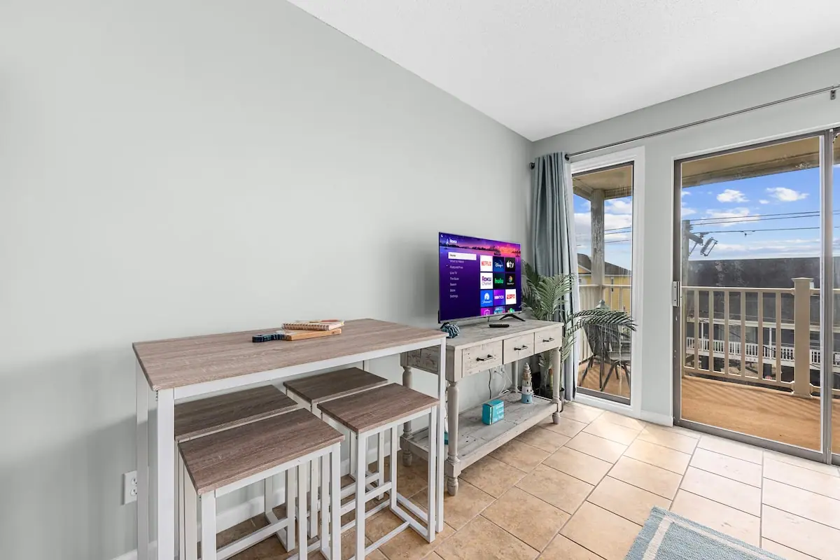 Television and dining table beside glass balcony doors