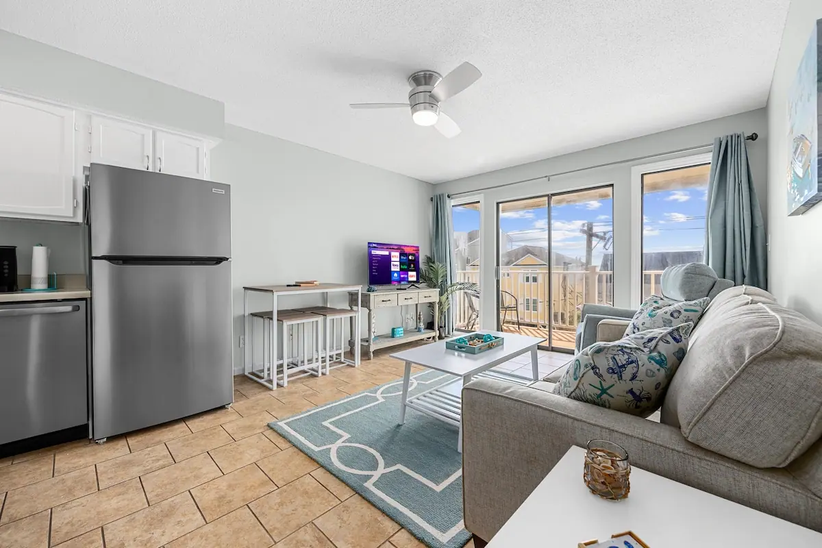 Living room sofa beside kitchenette and glass balcony doors
