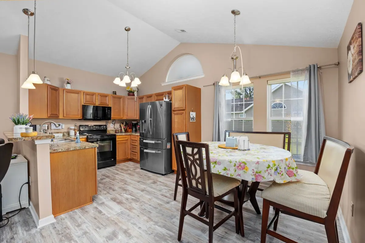 Kitchen with wood cabinets and round dining table near two windows