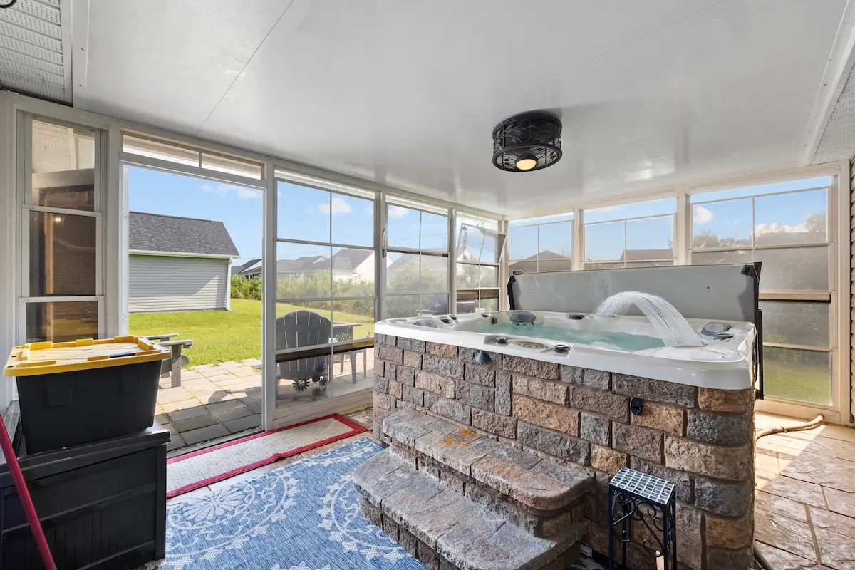 Hot tub on an enclosed porch with windows toward a grassy yard