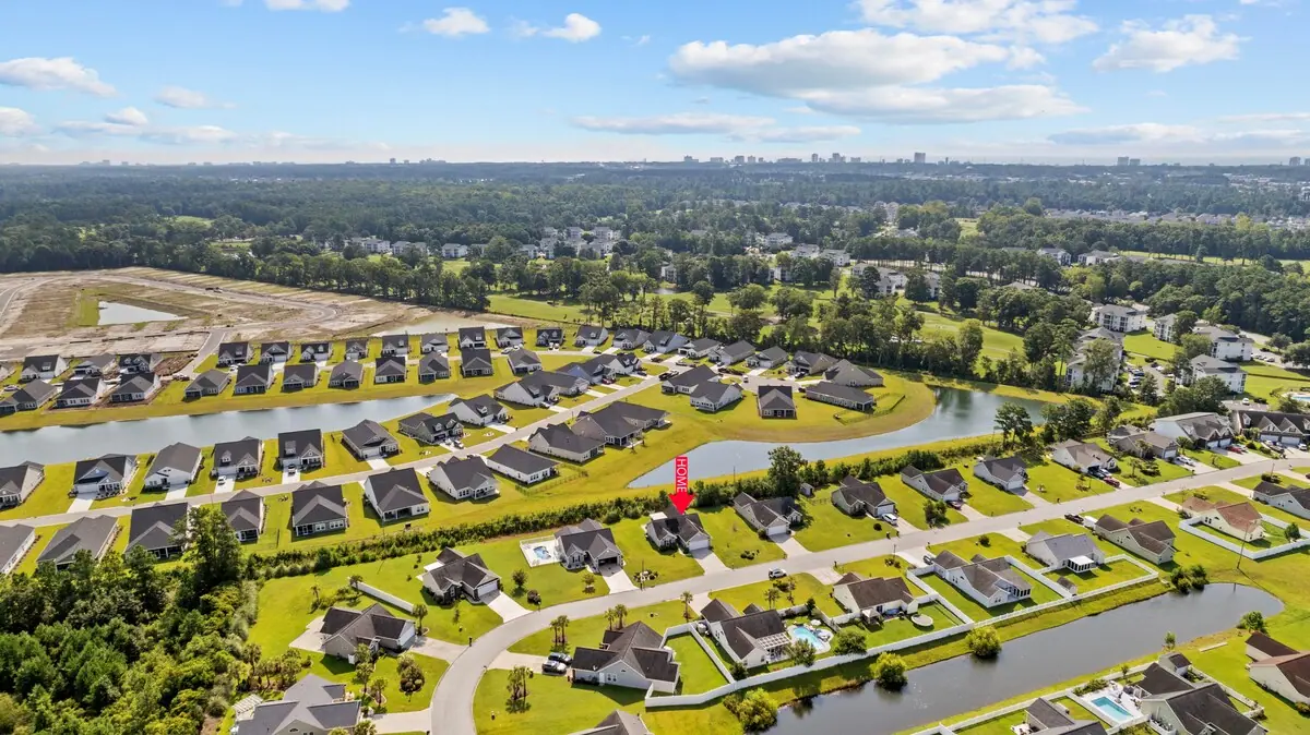 Aerial view of houses, pond, lawns, and tree-lined streets