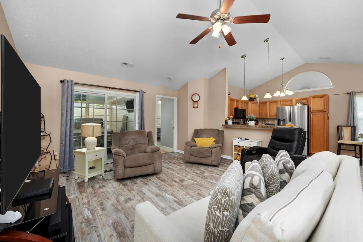 Living room with white sofa and armchairs beside the open kitchen